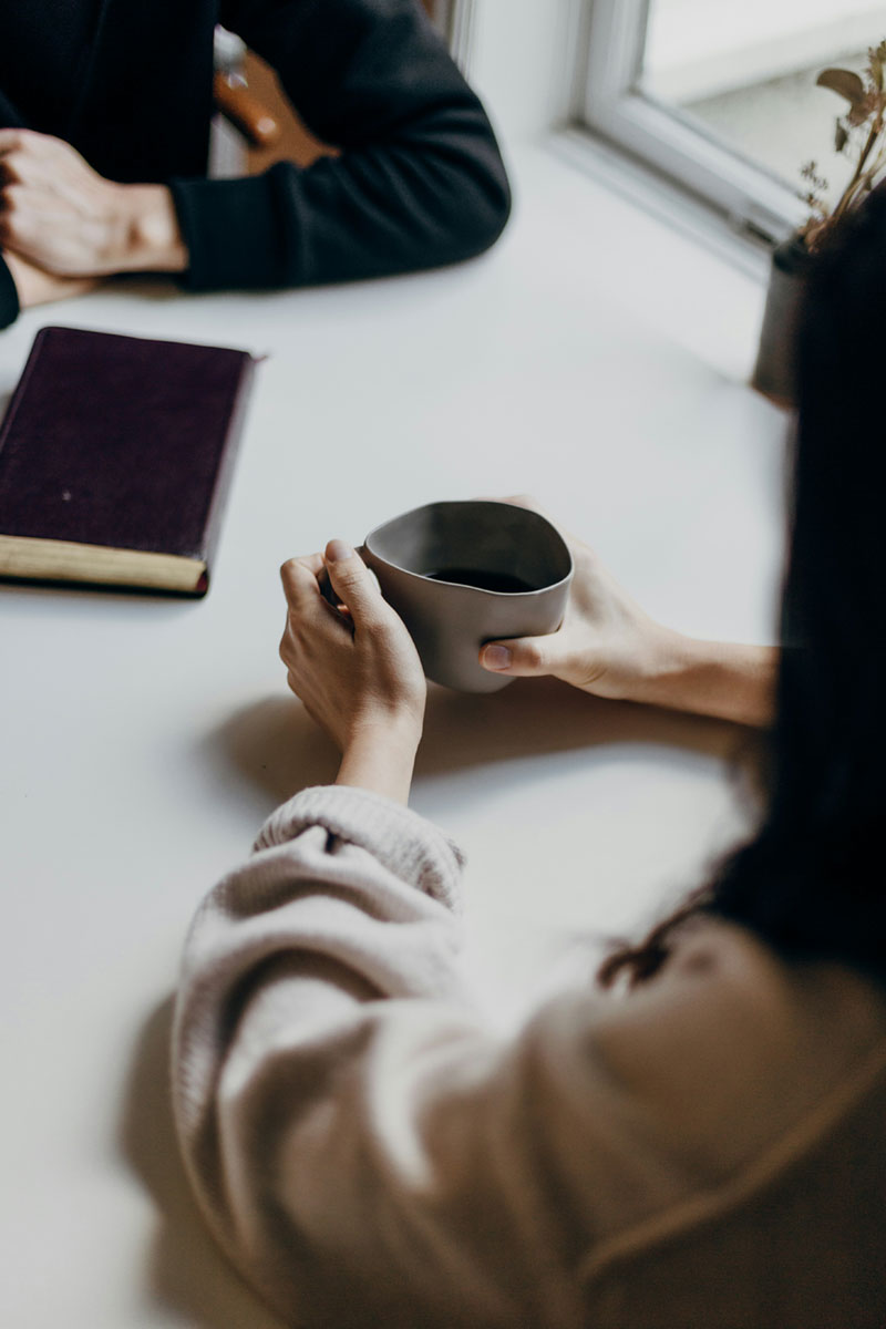 Woman sitting at a desk drinking coffee speaking with her therapist